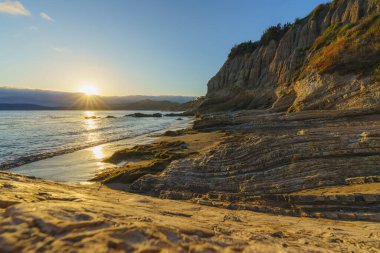 Pasifik Okyanusu gün batımı. Yaz akşamları, kayalık kıyı şeridi, ve güneş denizin üzerinde batarken gökyüzü parlıyor, California