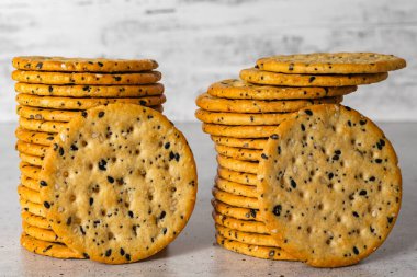 Sesame and poppy seed crackers close up on light grey background clipart