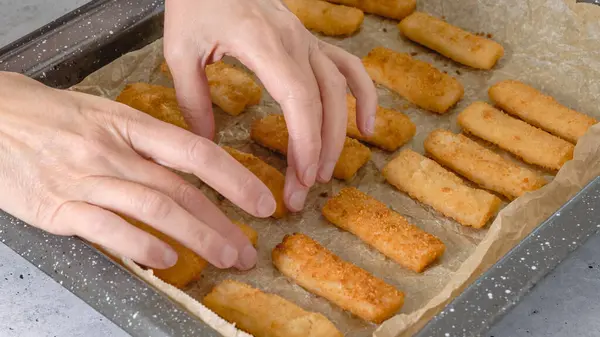 Baking pan with fish sticks close up on the kitchen table. Crunchy delicious lightly breaded with  bread crumbs fish sticks close-up