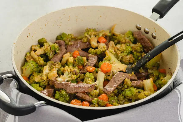 Beef and broccoli with stir fry sauce recipe. Delicious meal cooked in a frying pan, close-up on kitchen table