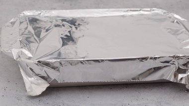 Masaya alüminyum folyoyla kaplanmış yemek kabı. Ispanaklı lazanya tarifi. Lazanyayı alüminyum folyoyla pişirmeden önce.