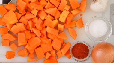 Tereyağlı kabak çorbası tarifi. Mutfak masasının üzerinde çiğ sebzeler. Kabuğu soyulmuş ve çekirdeksiz kabak kesme tahtasına yakın çekim, düz yatış