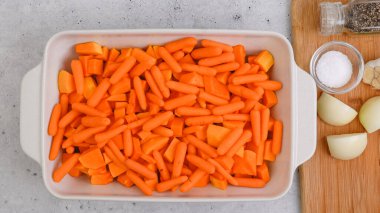 Kızarmış tereyağlı kabak çorbası tarifi. Soyulmuş ve çekirdeksiz kabak küpleri, havuç, soğan, sarımsak ve baharatlar mutfak masasındaki seramik fırın kabında yakın plan.