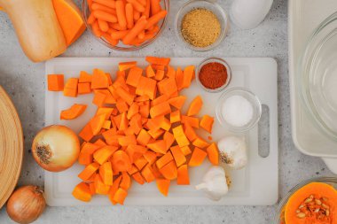 Yukardan soyulmuş tereyağlı kabak, havuç, sarımsak ve soğan yakın plan. Tereyağlı kabak çorbası tarifi, mutfak masasındaki malzemeler.