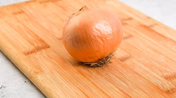 Peeling and cutting white onion on a cutting board. Vegetable soup recipe. Ingredients close-up on the kitchen table