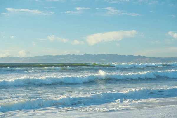 Sea waves beneath a quilt of fluffy clouds on a sunlit day, blending tranquility and awe-inspiring nature, California