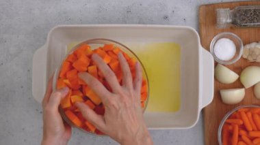 Kızarmış tereyağlı kabak çorbası tarifi. Soyulmuş ve çekirdeksiz kabak küpleri, havuç, soğan, sarımsak ve baharatlar mutfak masasındaki seramik fırın kabında yakın plan.