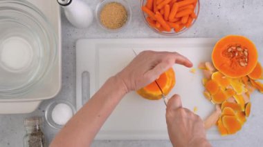 Kabak çorbası tarifi, hazırlık süreci. Çiğ sebzeler ve baharatlar mutfak masasına yakın plan, düz yatak. Kadın elleri kabak soyar, düz uzanır