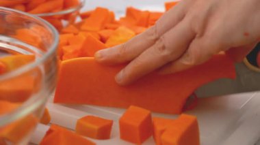 Tereyağlı kabak çorbası tarifi. Kadın balkabağı kesiyor. Mutfak masasının üzerinde çiğ sebzeler. Kabuğu soyulmuş ve çekirdeksiz kabak kesme tahtasına yakın çekim, düz yatış