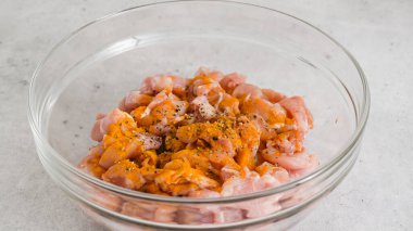 Doğranmış tavuğa zerdeçal ekliyorum. İçinde marine edilmiş tavuk eti karışımı olan cam kase.