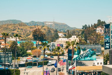 Los Angeles, Kaliforniya, ABD - 26 Nisan 2023. Hollywood tepeleri ve Hollywood tabelası, renkli reklam panoları, palmiye ağaçları, trafik, turistler