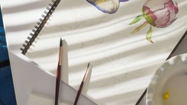 Suluboya resim. Fırçalar ve kâğıtlar pencerenin parlak güneş ışığında bir masanın üzerinde. Sanat, çizim öğrenme, hobi konsepti