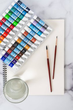 Suluboya setleri, kağıtlar, fırçalar, kalemler bir masanın üzerine yakın plan, düz yatak.