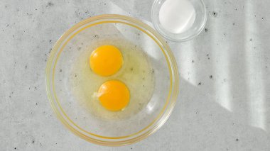 Cam kasede çiğ yumurta, cam kasede tuz açık gri arka planda yakın plan, uzayı kopyala.
