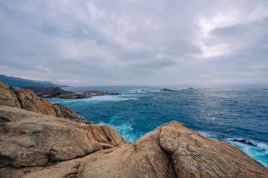 Kasvetli bir bulutlu günde Rocky plajı ve okyanus manzarası