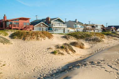 Kıyı kum tepelerinin arasına kurulmuş evler. Kaliforniya 'da küçük bir sahil kasabasında okyanus manzaralı güzel evler.