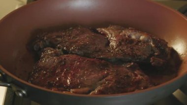 Biftek tavada cızırdıyor, fırının üzerinde yakın plan mutfak mükemmelliği anı..