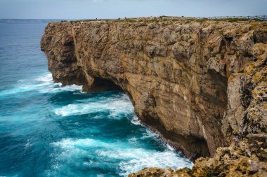 Kayalık kayalıkların ve arka planda açık gökyüzü olan Atlantik Okyanusu 'nun muhteşem manzarası. Algarve, Portekiz