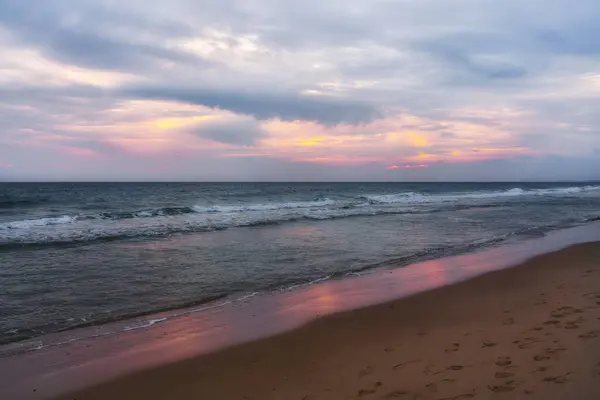 Pink sunset on the beach. Ocean, cloudy sky, and empty sandy beach at sunset, vibrant scene
