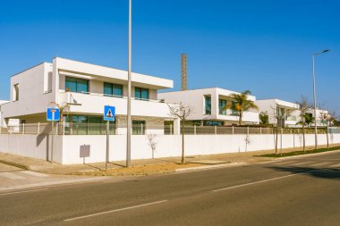 Şık, modern apartman daireleri cadde boyunca uzanır, arka planda parlak mavi gökyüzü.