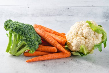Karnabahar, brokoli ve yakın plan havuç. Açık gri arkaplanlı taze organik sebzeler grubu, kopyalama alanı