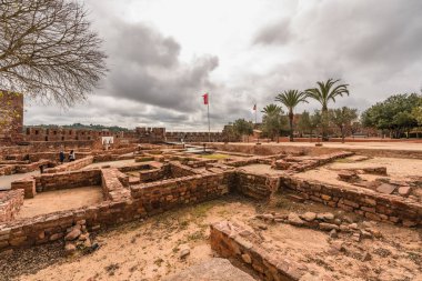 Ziyaretçiler bulutlu bir gökyüzünün altındaki tarihi Silves Şatosu 'nun geniş avlusunu keşfediyorlar. Silves, Portekiz, 3 Ocak 2024