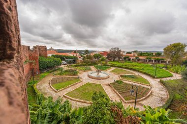 Ancient stone walls of Silves Castle frame a view of the gardens and the landscape beyond. Silves, Portugal, January 3, 2024 clipart