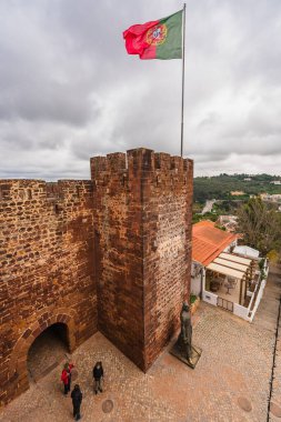 Silves Kalesi 'nin terasotta döşemeli çatılarında Portekiz bayrağı var, geniş bir manzaraya bakıyor. Silves, Portekiz, 3 Ocak 2024