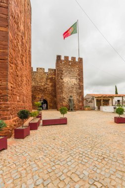 Ortaçağ Silves Kalesi Portekiz bayrağıyla nöbet tutuyor ve tarih meraklılarını davet ediyor. Silves, Portekiz, 3 Ocak 2024