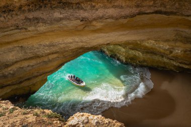 Portekiz, Algarve 'deki Benagil Mağarası' nın içindeki turkuaz suları turistler keşfeder..