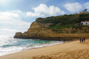 Kireçtaşı kayalıkları berrak mavi sularla çevrili tenha bir kumsal. Algarve, Portekiz, 2 Ocak 2024