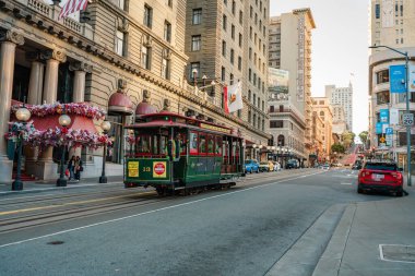 San Francisco, Kaliforniya, 8 Nisan 2024. San Francisco 'nun işlek caddesi boyunca tarihi binalar tarafından çevrelenmiş olan raylardan araç yaklaşıyor..