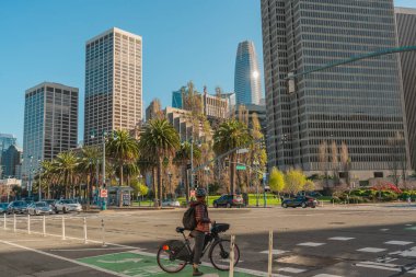 San Francisco, Kaliforniya, 8 Nisan 2024. The Embarcadero 'daki sokak sahnesinde bisikletçiler ve yayalar yüksek binalar ve palmiye ağaçlarıyla çevrili..