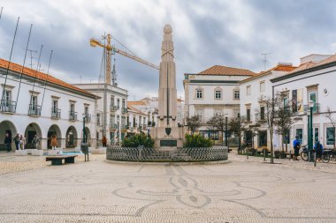 Tavira, Portekiz, 8 Ocak 2024. Portekiz 'in Tavira kentindeki şehir meydanında beyaz binalarla çevrili önemli bir anıt ve karmaşık kaldırım taşı desenleri var..