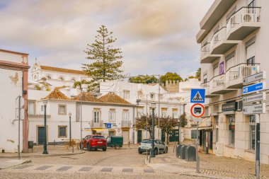 Tavira, Portekiz, 8 Ocak 2024. Portekiz, Tavira 'da sokak manzarası, kaldırım taşlı yollar, geleneksel ve modern binaların karışımı, ve çeşitli sokak tabelaları.