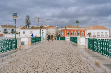 Tavira, Portekiz, 8 Ocak 2024. Portekiz 'in Tavira kentindeki Roma köprüsünde kaldırım taşları ve tarihi binalarla yaya geçidi..