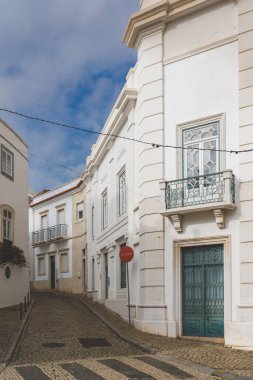 Portekiz, Tavira 'da dar kaldırım taşı caddesinde beyaz binalar ve köşede 