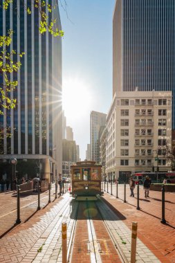 San Francisco, Kaliforniya, 8 Nisan 2024. Tarihsel teleferik San Francisco 'da gökdelenlerle çevrili bir caddeye çıktı ve güneş ışığıyla yıkandı..