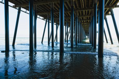 İskelenin altında. Uzun bir ahşap iskele, ve okyanus dalgaları, dramatik bir sahne, California Merkez Sahili