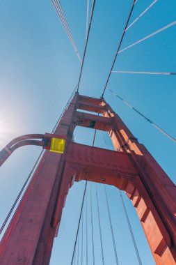 Golden Gate 'in mimari ve süspansiyon kablolarının dramatik yükseliş görüntüsü.