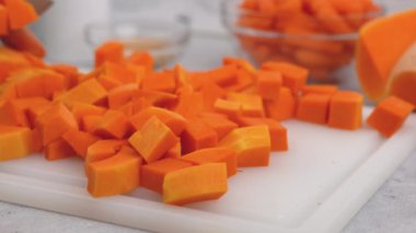 Tereyağlı kabak çorbası tarifi. Mutfak masasındaki kesme tahtasına yakın plan tereyağı ezmesi küpleri.