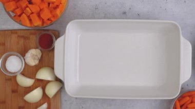 Kızarmış tereyağlı kabak çorbası tarifi. Soyulmuş ve çekirdeksiz kabak küpleri, havuç, soğan, sarımsak ve baharatlar mutfak masasındaki seramik fırın kabında yakın plan.