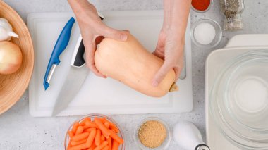 Tereyağlı kabak çorbası tarifi. Mutfak masasının üzerinde çiğ sebzeler. Tereyağlı kabak, havuç, soğan, sarımsak, biraz baharat, kadın eli.