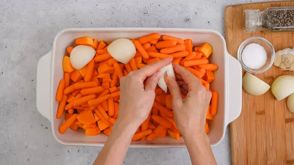 stock image Roasted butternut squash soup recipe. Peeled and seedless squash cubes, carrot, onion, garlic, and spices close-up in a ceramic baking dish on the kitchen table