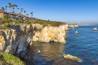 Kayalık uçurumların ve sakin okyanusların üzerine konmuş evleri olan manzaralı kıyı manzarası..