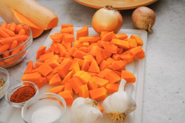 Soyulmuş ve doğranmış tereyağlı kabak, havuç, sarımsak ve soğan yakın plan. Tereyağlı kabak çorbası tarifi, mutfak masasındaki malzemeler.