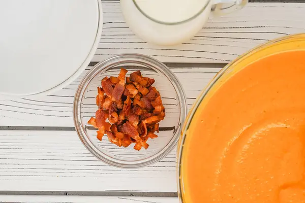 stock image Roasted butternut squash soup served with a crispy bacon and heavy cream topping, close-up in a bowl on a white wooden board