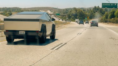 Los Angeles, California, USA. July 31, 2024. Tesla Cybertruck drives on a busy California highway under a clear blue sky. clipart