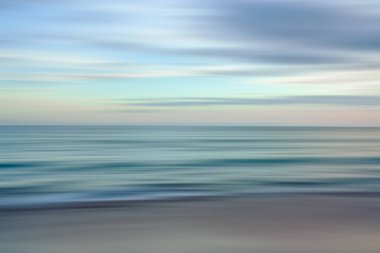 Dynamic lines of blue and orange blur together in this abstract depiction of the ocean at sunset clipart