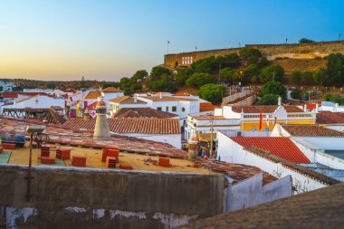 Lively atmosphere in Castro Marim, Portugal, with festivalgoers enjoying the medieval-themed celebration at sunset. clipart